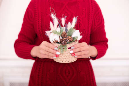 Beautiful female hands with winter manicure nails, Christmas design, holding bouquetの写真素材