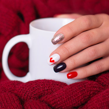 Beautiful female hand with romantic manicure nails, heart and Valentine's day design, holding cupの写真素材