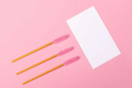 Close up view of golden brushes for eyebrows and eyelashes extensions on pink background with place...