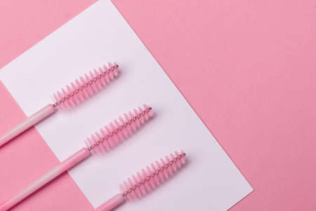 Close up view of brushes for eyebrows and eyelashes extensions on pink background with place for...