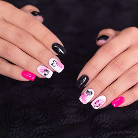 Beautiful female hands with fashion manicure nails, hearts and Valentine's day design, on black...