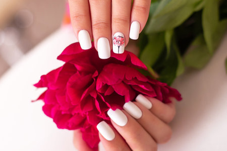 Beautiful female hands with romantic manicure nails, white gel polish, peonies flowers designの写真素材