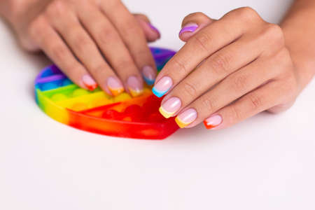 Beautiful female hands with colorful manicure nails holding toy, pop itの写真素材