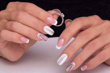 Beautiful female hands with wedding manicure nails with ring on white backgroundの写真素材