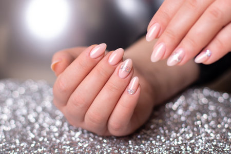 Beautiful female hands with wedding manicure nails, pink gel polish with silver glitterの写真素材