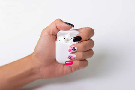 Female hands with creative manicure nails holding earphone in white case