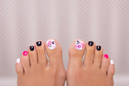 Beautiful female feet with fashion pedicure nails, pink, white and black gel polish, heart designの写真素材