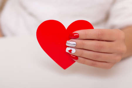 Beautiful female hand with romantic manicure nails, holding heart, valentine's day designの写真素材