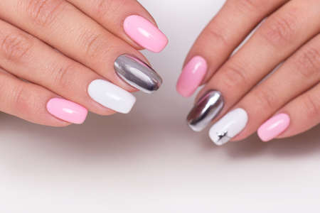Beautiful female hands with colorful manicure nails, pink and silver colored gel polishの写真素材