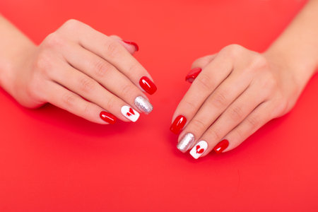 Beautiful female hands with romantic manicure nails, red gel polish, heart and Valentine's day designの写真素材