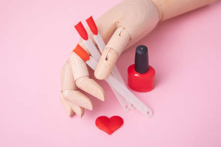 Wooden hand near red palette for manicure nails and gel polish, heart designの写真素材