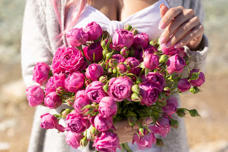 Female hands with french manicure nails holding beautiful bouquet of pink peoniesの写真素材