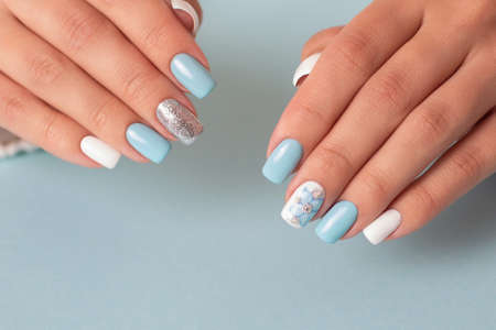 Beautiful female hands with romantic manicure nails, blue and white gel polishの写真素材