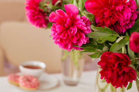 Client place in hairdressing beauty salon with cup of tea, donuts and peonies flowersの写真素材