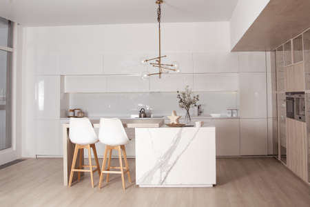Modern kitchen in beige colors, table, chairs and electronicsの写真素材