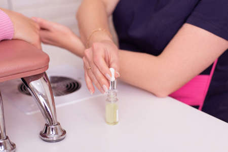 Manicure master gloves applying oil for care and treatment on nailsの写真素材
