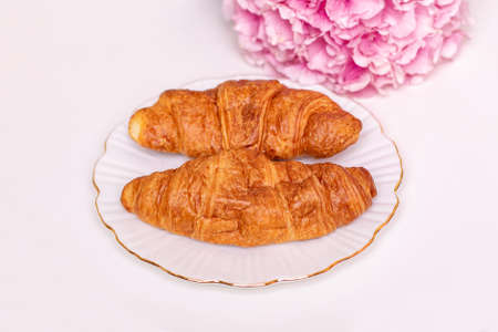 Croissants on plate with hydrangea flower on white backgroundの写真素材