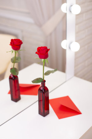 Red rose and envelope with copy space, on table in beauty salon. Valentine's day background, love and romance.の写真素材