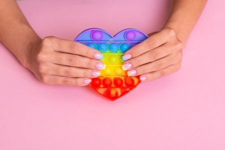 Beautiful female hands with colorful manicure nails holding toy, pop itの写真素材