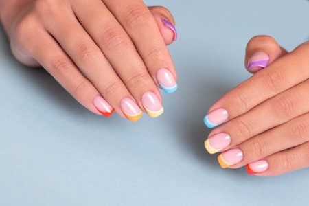 Beautiful female hands with colorful manicure nails with rainbow designの写真素材