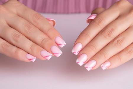 Beautiful female hands with pink and white manicure nails, sparkling french designの写真素材