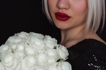 Close up view of beautiful female lips with professional red lipstick on white roses backgroundの写真素材
