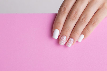 Beautiful female hand with pink and white manicure nails, flower designの写真素材