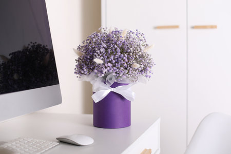 Bouquet of beautiful violet flowers on office desk near computerの写真素材