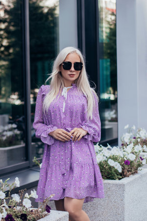 Young beautiful blonde hair woman in purple dress walking near business centerの写真素材