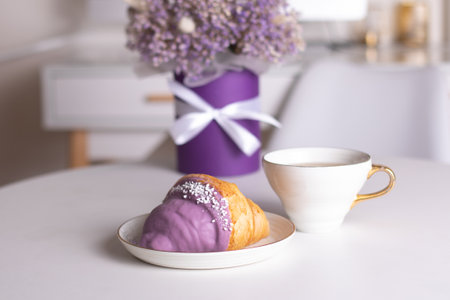 Cup of tea and berry croissant, bouquet of violet flowersの写真素材