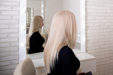 Female back with long, straight, healthy, blonde hair, on hairdressing salon backgroundの写真素材