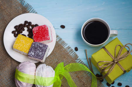 Cooked black coffee with sweet marshmallow on a blue wooden table