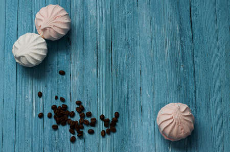 Cooked black coffee with sweet marshmallow on a blue wooden table