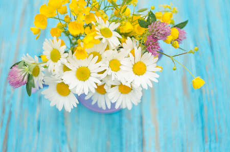 Bouquet of wild flowers of different colors in the vase outdoors or growing on fieldの写真素材