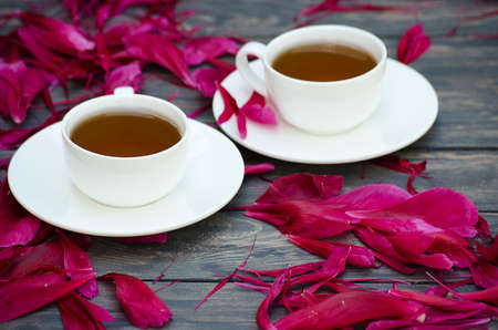 Hot tea and peony petals on dark wooden backgroundの写真素材