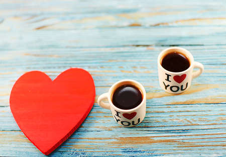 in the pots there is hot coffee and a heart on the wooden background for breakfastの写真素材