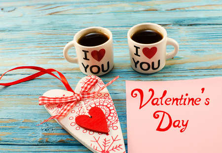 in the pots there is hot coffee and a heart on the wooden background for breakfast