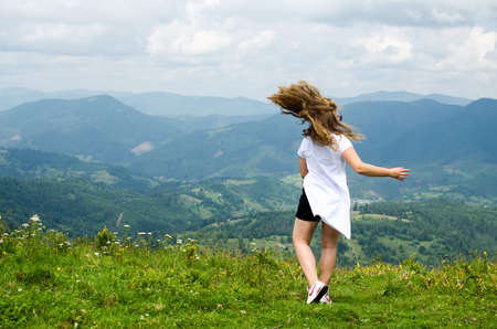 A young girl loves to travel and conquer the peaks of the mountains, she is happyの写真素材
