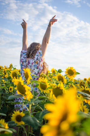 Happy girl with blond long hair on a field of sunflowers in summer outdoors dayの写真素材