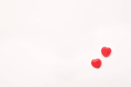 two little Red Valentine's day heart shape candy on empty white paper background. Love Concept. Minimalism style. Knolling top view.の写真素材