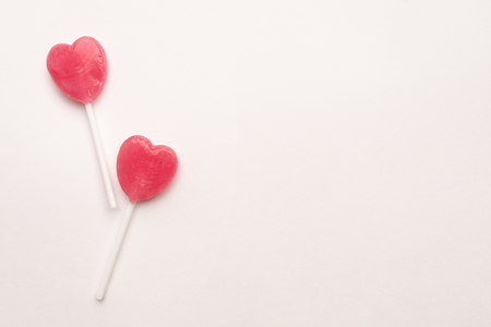 two Pink Valentine's day heart shape lollipop candy on empty white paper background. Love Concept. Knolling top view. Minimalism colorful hipster style.の写真素材