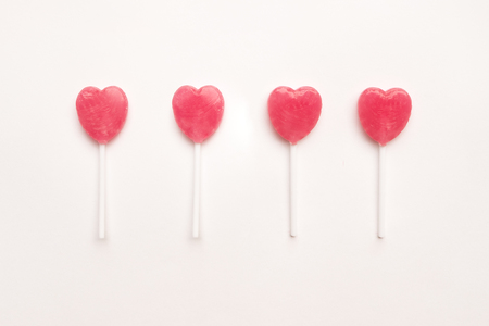four two Pink Valentine's day heart shape lollipop candy on empty white paper background. Love Concept. Knolling top view. Minimalism colorful hipster style.の写真素材