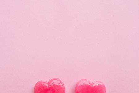 two Pink Valentine's day heart shape lollipop candy on empty pastel pink paper background. Love Concept. top view. Minimalism colorful hipster style.の写真素材