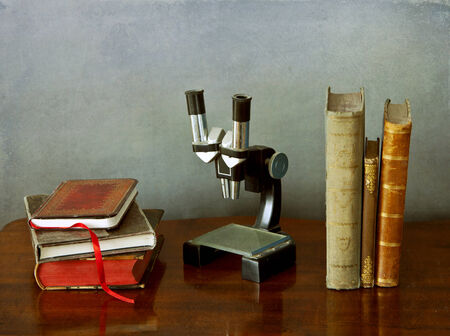 Interior still life: an old microscope and antique books on a wooden tableの写真素材