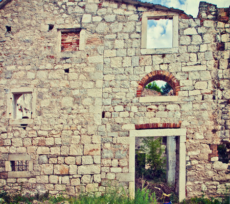 Front facade of  a dilapidated and abandoned  building, made of stone block and bricks.のeditorial素材