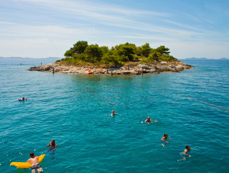 CROATIA, DALMATIAN COAST - AUGUST 20,2014. Tourists swim leisurely in Adriatic blue sea near a small island along the Dalmatian coast on a beautiful summer dayのeditorial素材
