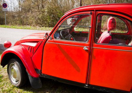 Vintage bright red Citroen 2 CV parked on street, lateral view