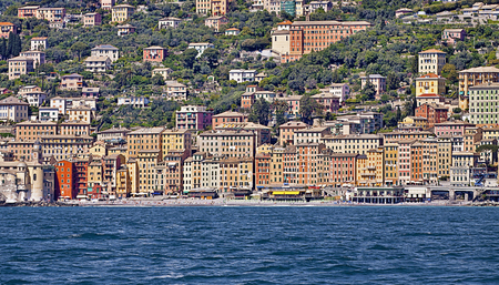 Panoramic view from the sea of Camogli, Italy, touristic fisher village on the Ligurian coast with colorful tall houses and pebble beach with bath facilitiesの写真素材