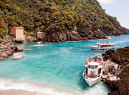 Liguria, Italy - view of San Fruttuoso bay near Genoa, a paradise angle accessible only by a pedestrian path from the hill above or by sea. A water bus motorboat is anchored at a rudimental pier to embark tourists.のeditorial素材
