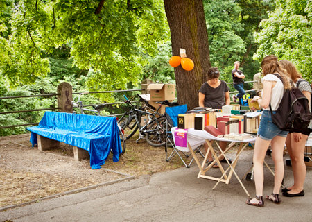 Book flea market with beautiful warm weather at the Isar river promenade in Munich center: used books to read, browse and buy under the trees with a rive-gauche-like charming feelingのeditorial素材